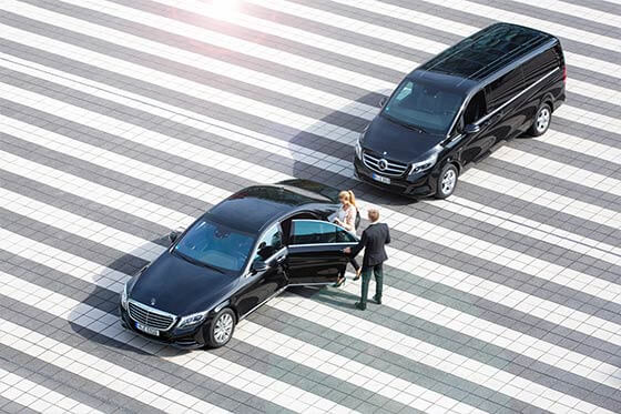 Eine Limousine und ein Minivan mit Chauffeur auf einem Rollfeld.